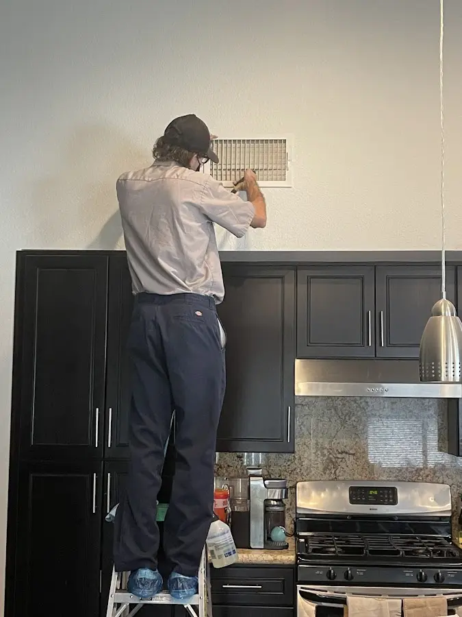 Technician inspecting an air vent during HVAC service in Contra Costa Centre
